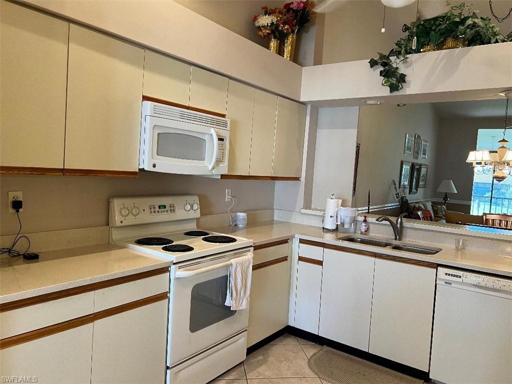 501 Veranda Way, Unit G204 Naples, FL 34104 - Photo 7 of 7 a kitchen with white cabinets and white appliances