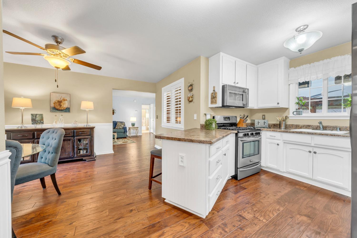 10092 Smith Road Grass Valley, CA 95949 - Photo 24 of 58 a kitchen with granite countertop a stove top oven a sink a dining table and chairs with wooden floor