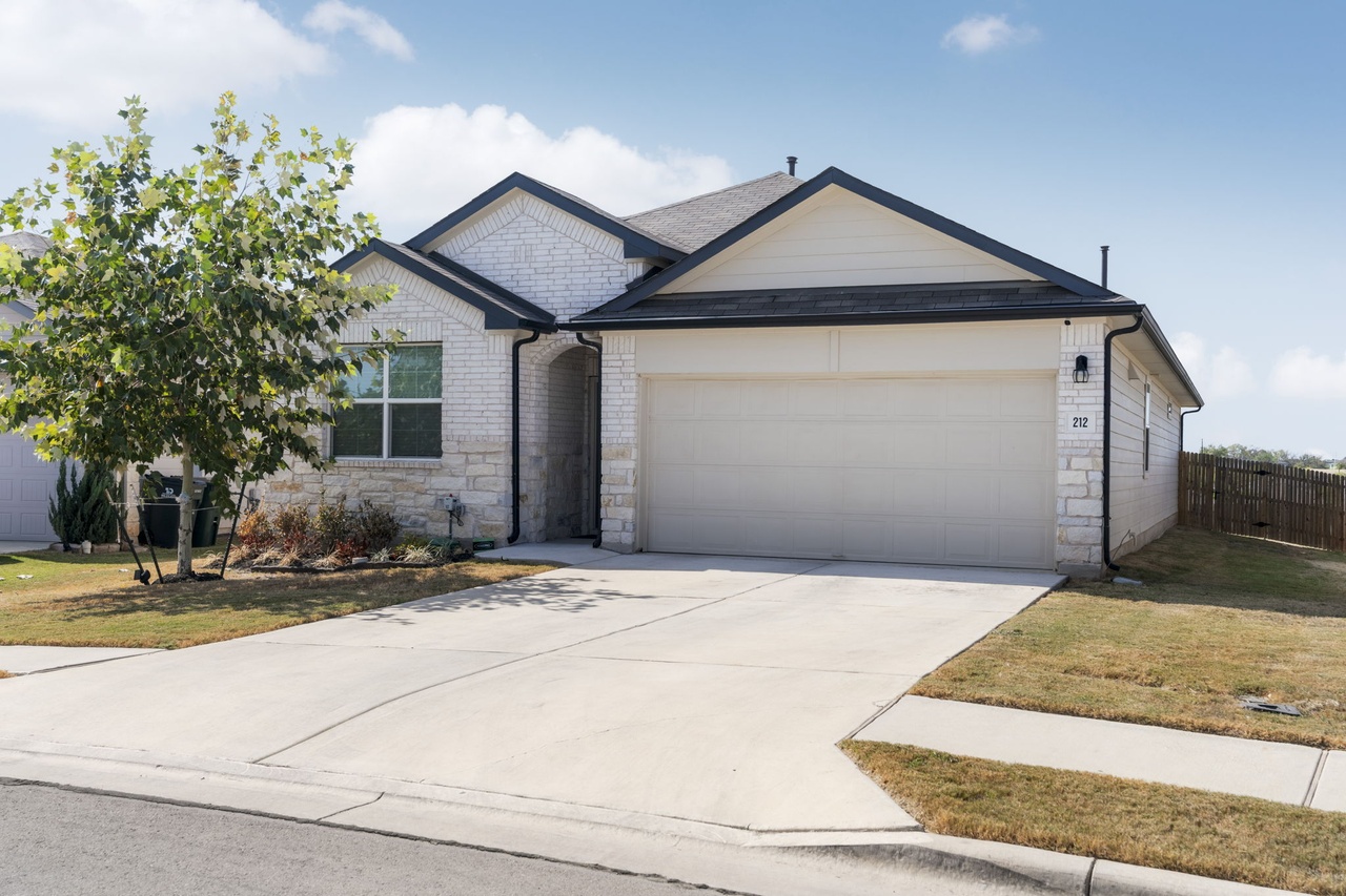 212 Apache Plum Drive Kyle, TX 78640 - Photo 8 of 21 Single story home featuring driveway, a garage, stone siding, and brick siding