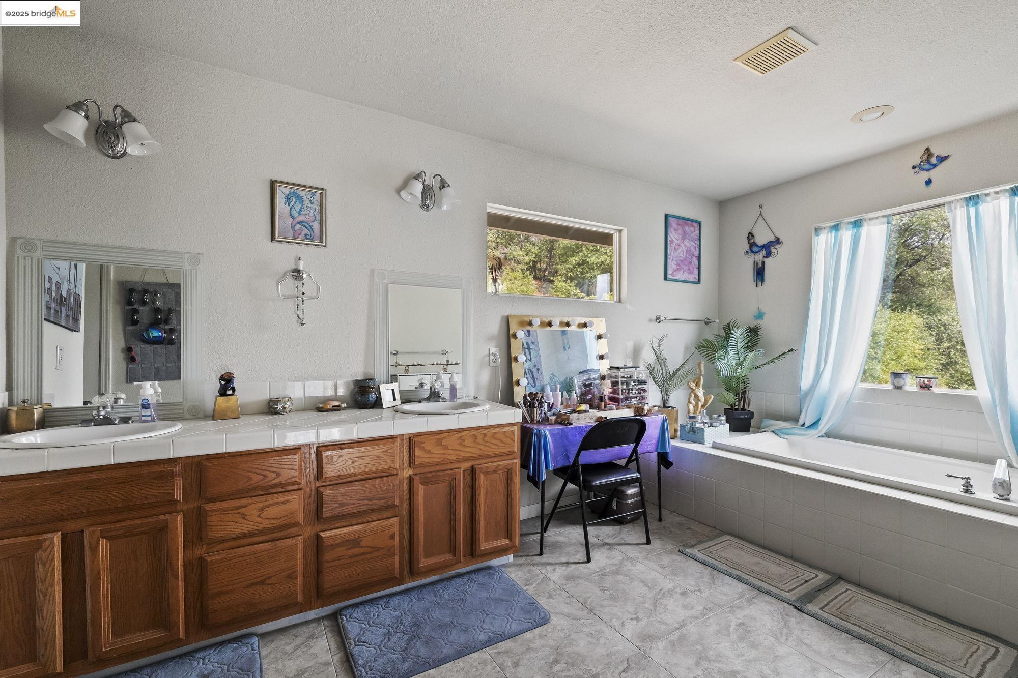 20588 Upper Hillview Drive Sonora, CA 95370 - Photo 14 of 42 a spacious bathroom with a double vanity sink a large mirror a bathtub and next to a window