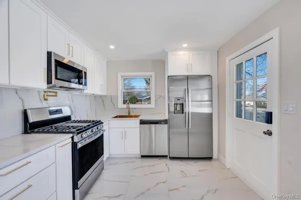 a kitchen with stainless steel appliances granite countertop a refrigerator oven a sink dishwasher and white cabinets with wooden floor