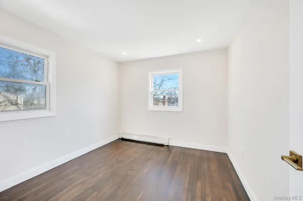 an empty room with wooden floor and window