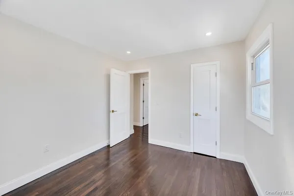 a view of an empty room with wooden floor and closet