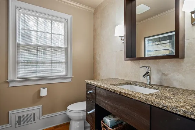 a bathroom with a granite countertop sink mirror vanity and toilet