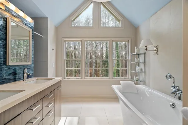 a bathroom with a tub a sink and a large window