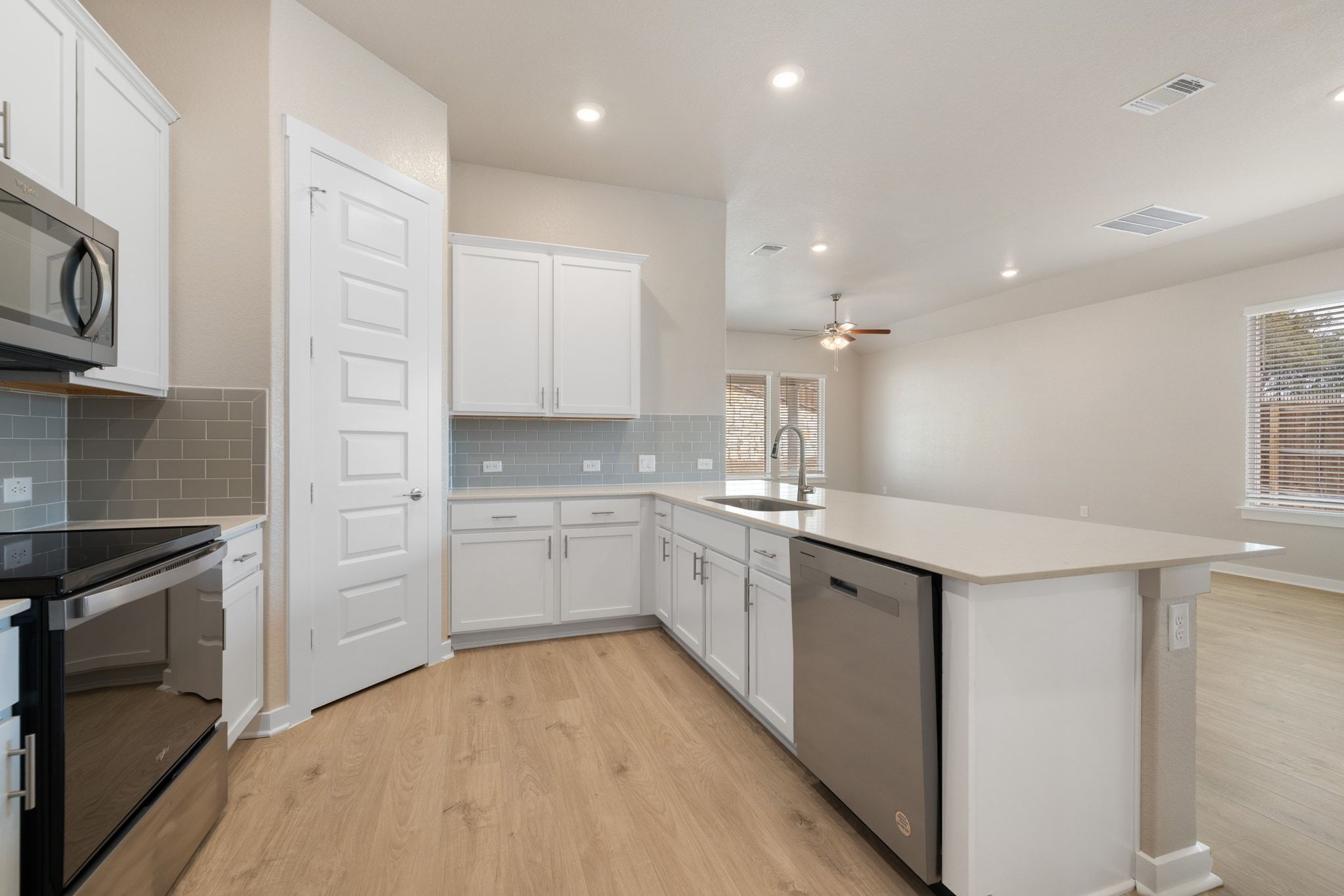 309 Barton Run Drive Georgetown, TX 78628 - Photo 10 of 35 Kitchen featuring white cabinets, stainless steel appliances, a peninsula, light wood-style flooring, and recessed lighting