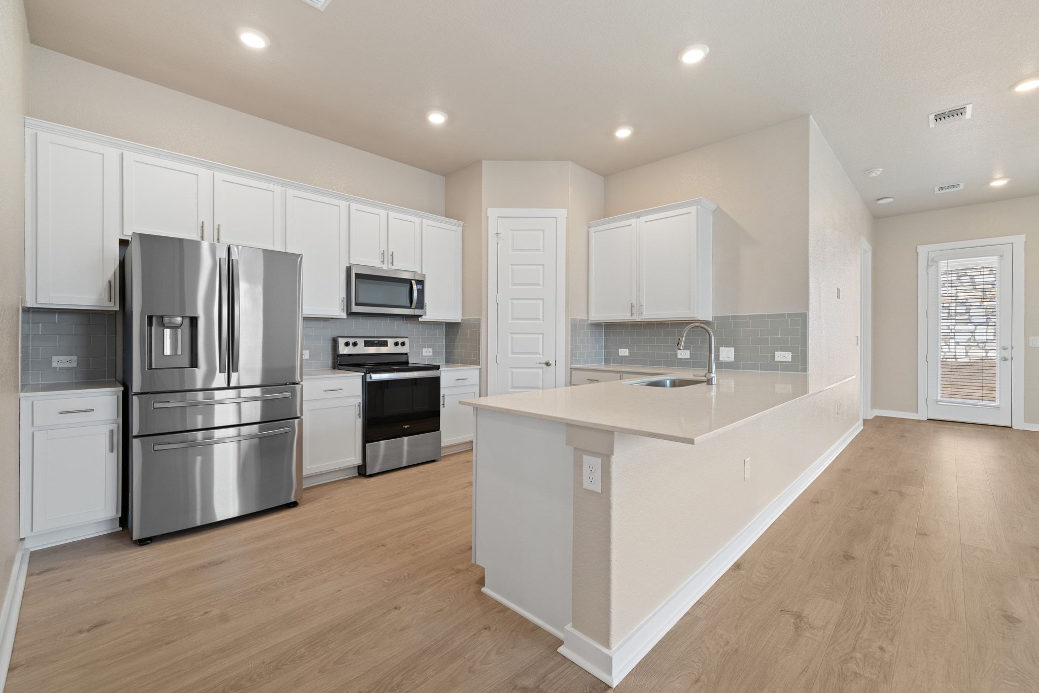 309 Barton Run Drive Georgetown, TX 78628 - Photo 9 of 35 Kitchen featuring stainless steel appliances, white cabinetry, a peninsula, light wood-style floors, and tasteful backsplash