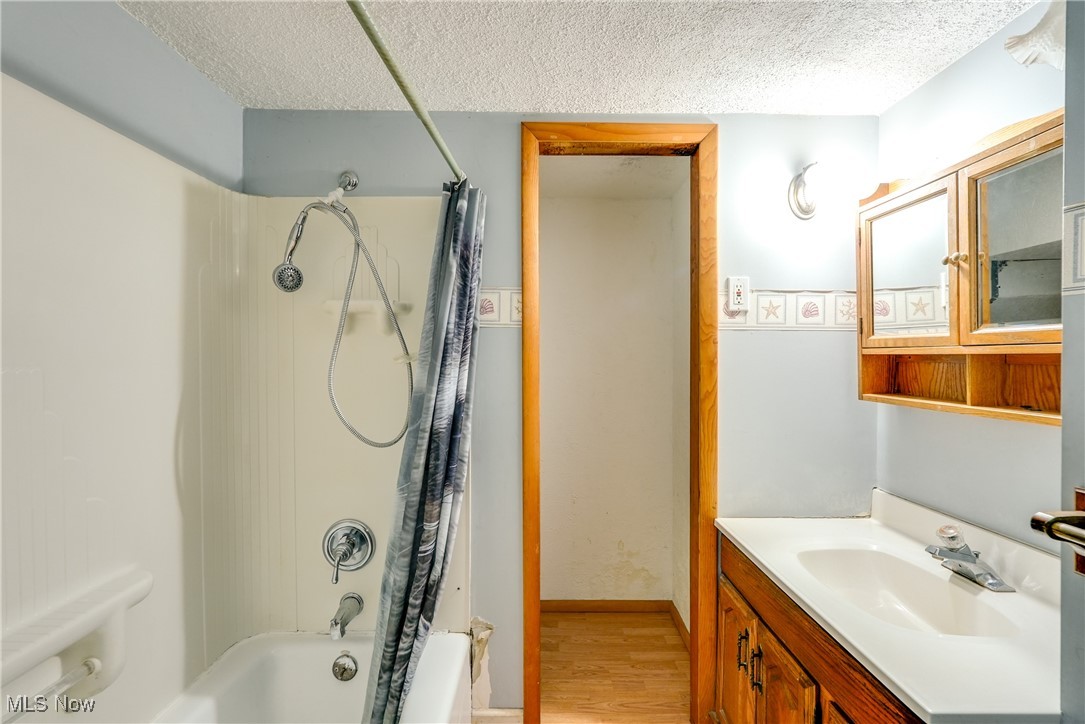 2123 Martin Road Mogadore, OH 44260 - Photo 17 of 35 Bathroom featuring a textured ceiling, shower / tub combo, wood finished floors, and vanity