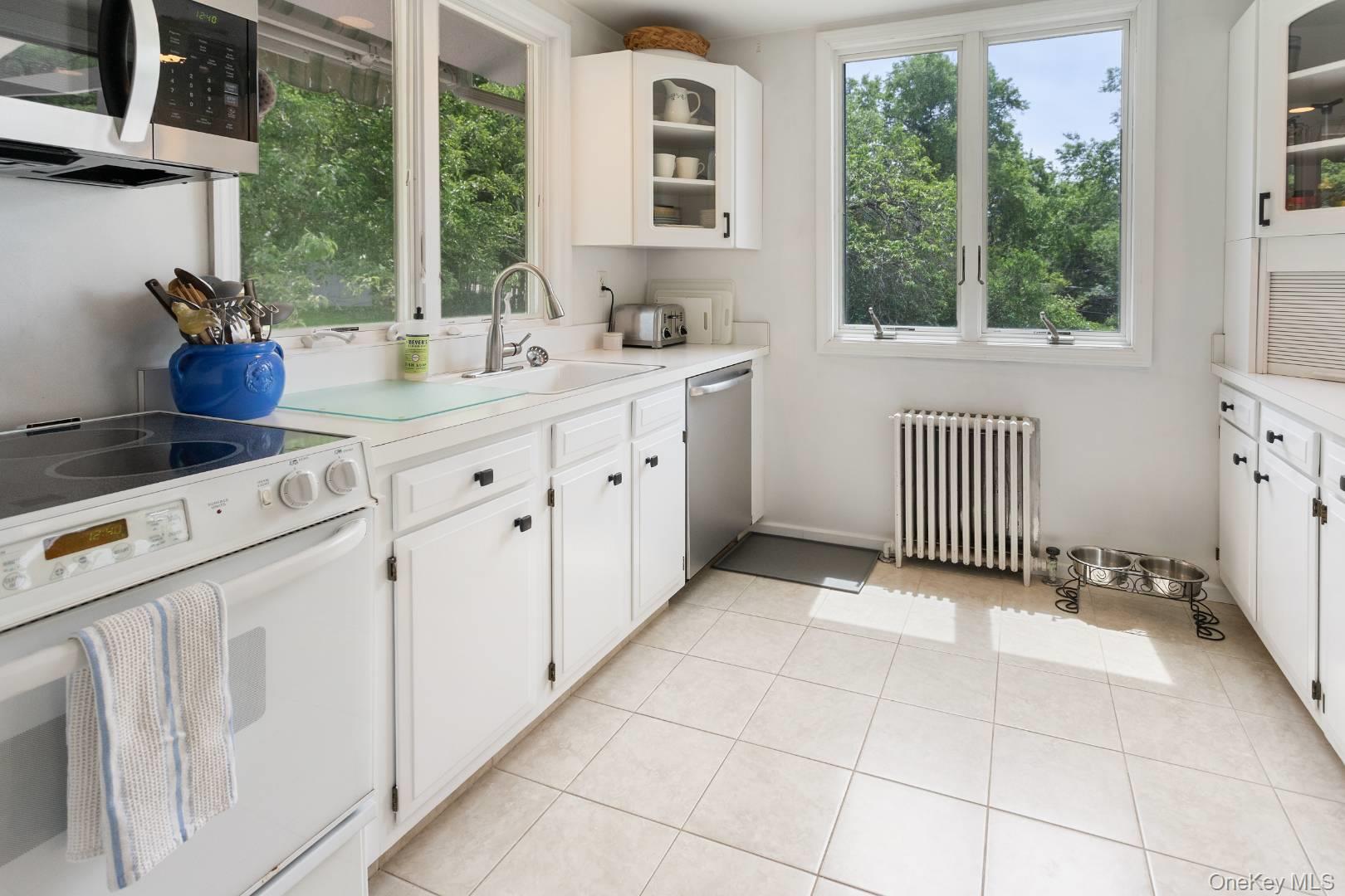16 South Beach Road Southampton, NY 11968 - Photo 11 of 14 Kitchen featuring glass insert cabinets, stainless steel appliances, white cabinets, and light countertops