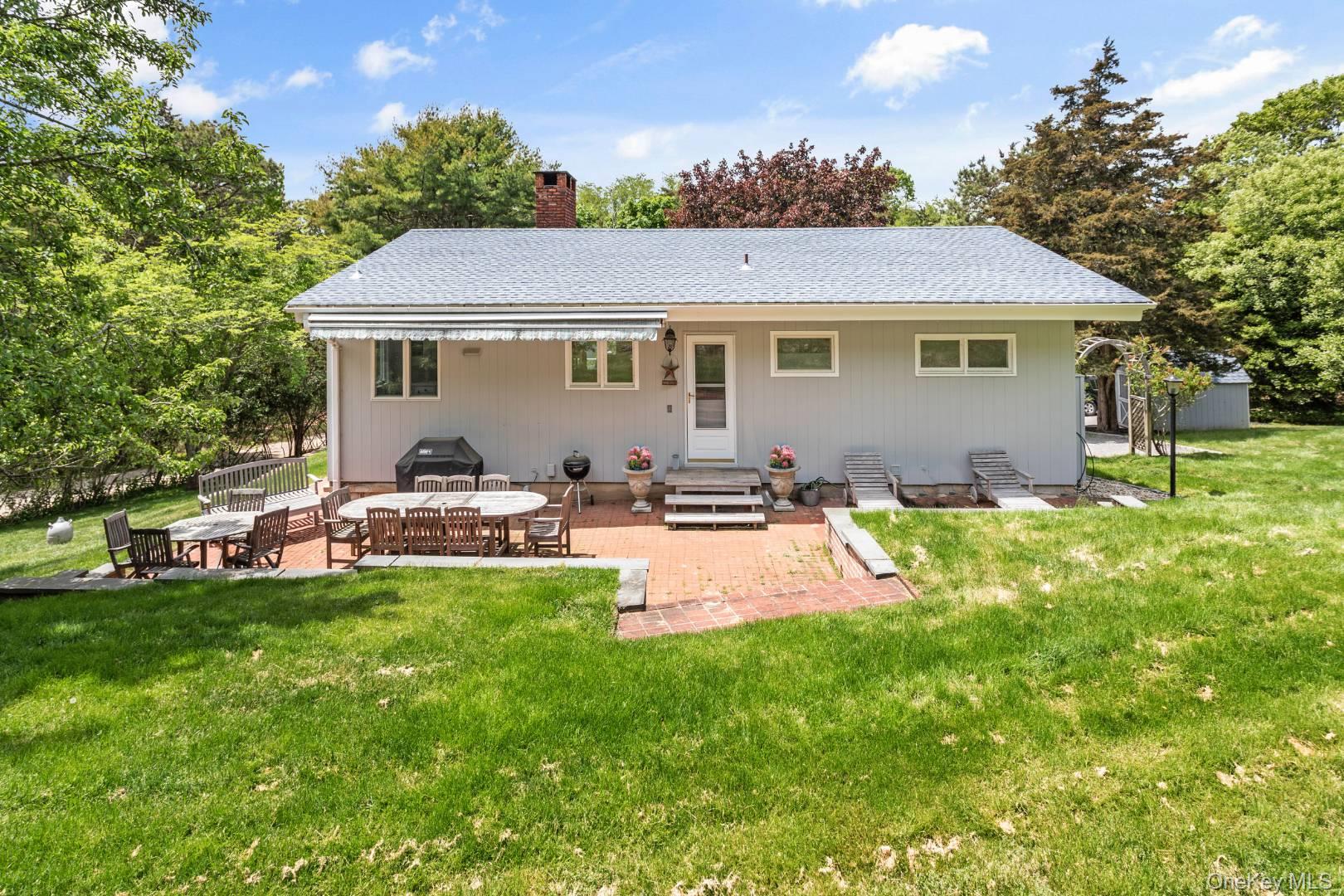 16 South Beach Road Southampton, NY 11968 - Photo 3 of 14 Back of house with a patio, a lawn, a chimney, and a shingled roof