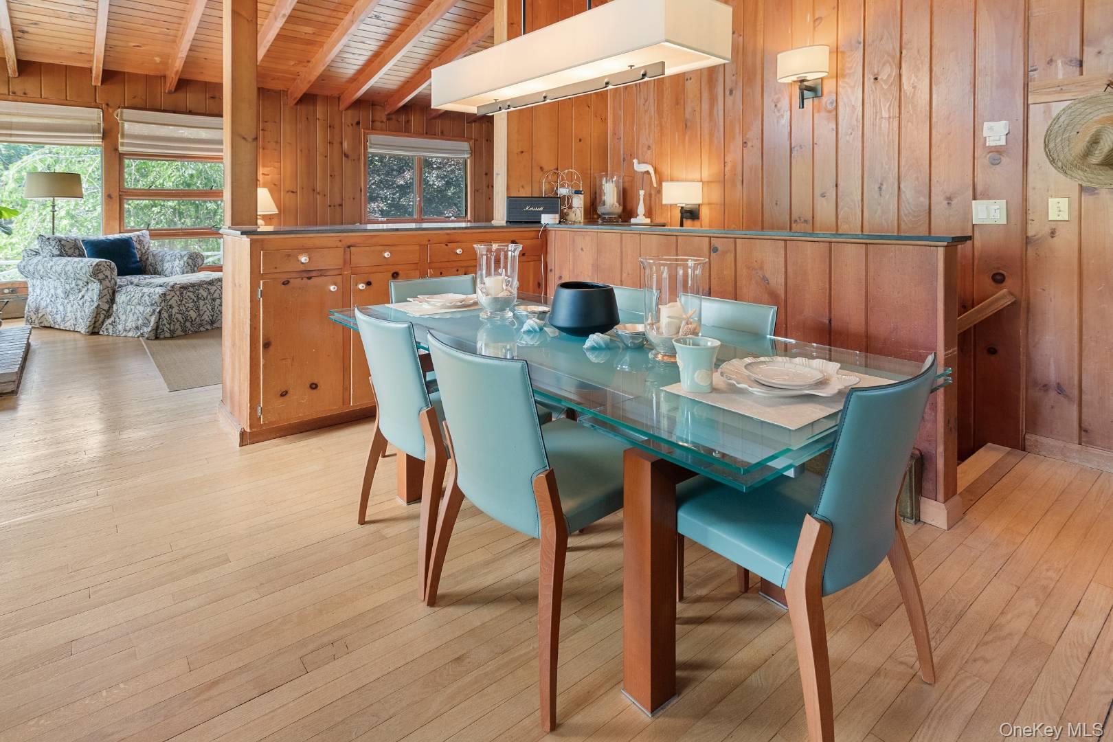 16 South Beach Road Southampton, NY 11968 - Photo 8 of 14 Dining space featuring light wood-style floors, wood walls, and a wooden ceiling with exposed beams