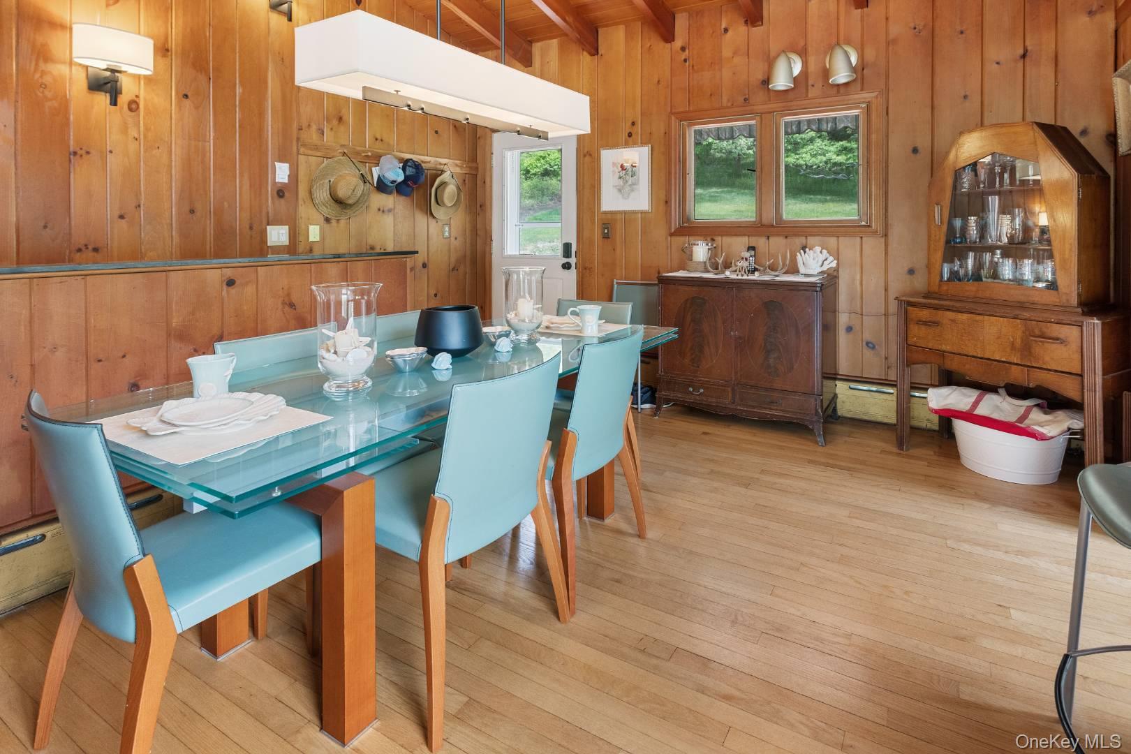 16 South Beach Road Southampton, NY 11968 - Photo 9 of 14 Dining area featuring beamed ceiling, light wood finished floors, wooden walls, and baseboard heating
