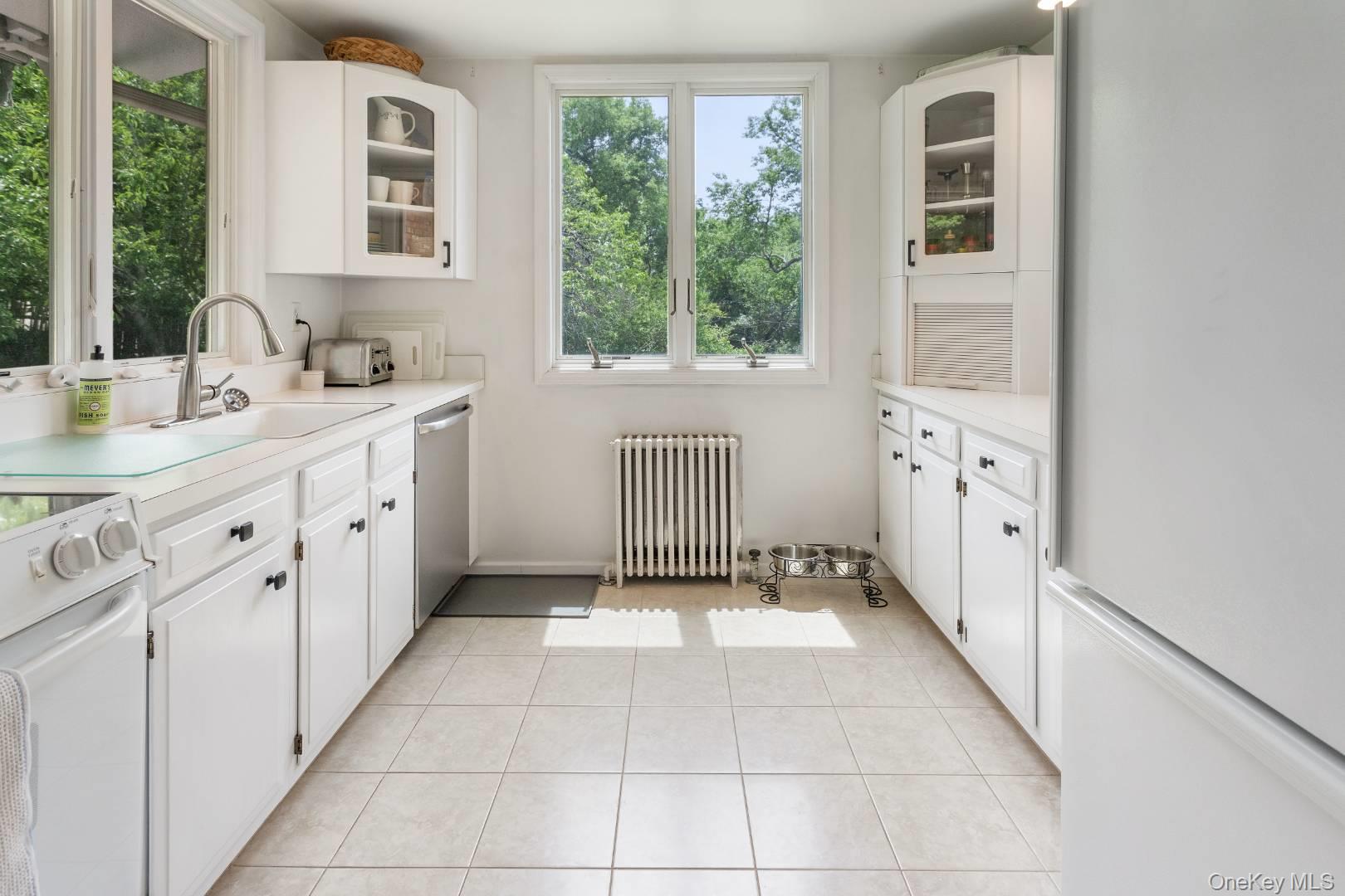 16 South Beach Road Southampton, NY 11968 - Photo 10 of 14 Kitchen with glass insert cabinets, white appliances, white cabinetry, and light countertops