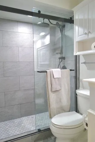 a white toilet sitting next to a shower