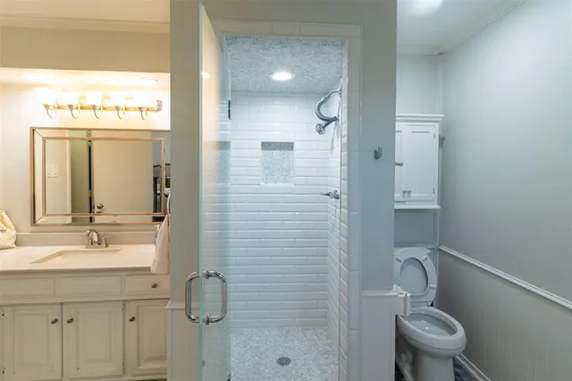 a bathroom with a granite countertop sink a toilet and shower