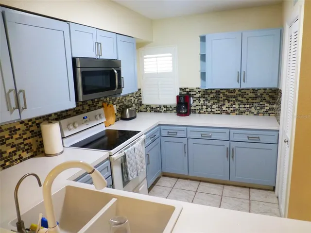 a kitchen with white cabinets a sink and a stove with wooden floor