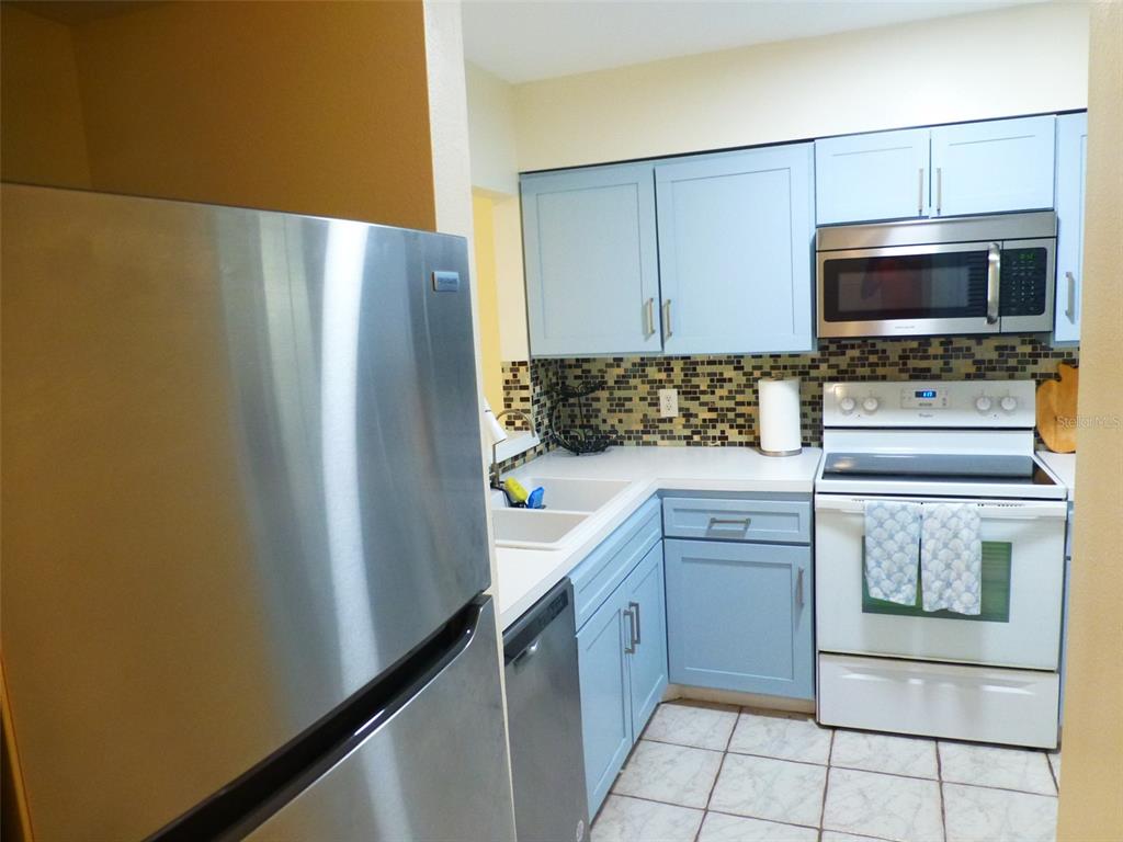 5557 Sea Forest Drive, Unit 215 New Port Richey, FL 34652 - Photo 7 of 40 a kitchen with a refrigerator and microwave