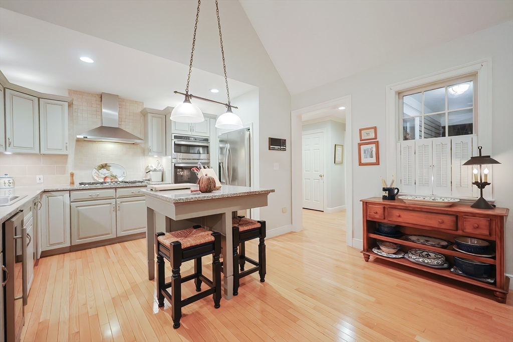 12 Highcroft Way, Unit 12 Hopkinton, MA 01748 - Photo 7 of 37 a kitchen with stainless steel appliances a table chairs in it and wooden floors