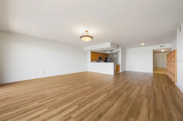 a view of empty room with wooden floor and window