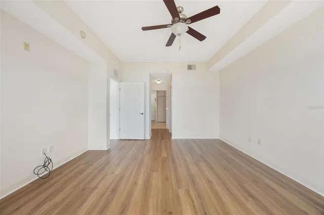 an empty room with wooden floor and a ceiling fan
