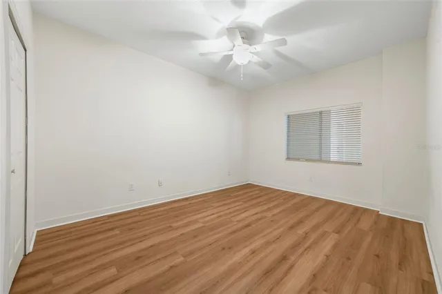 an empty room with wooden floor and fan