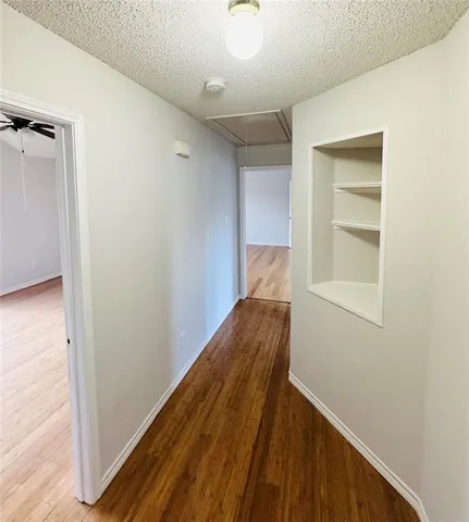 a view of a hallway with wooden floor and closet