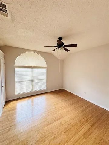 an empty room with wooden floor fan and windows