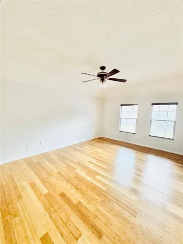 a view of empty room with wooden floor and windows