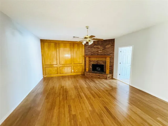 an empty room with wooden floor fireplace and windows