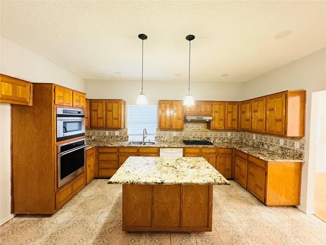 a kitchen with stainless steel appliances granite countertop a stove a sink and a refrigerator