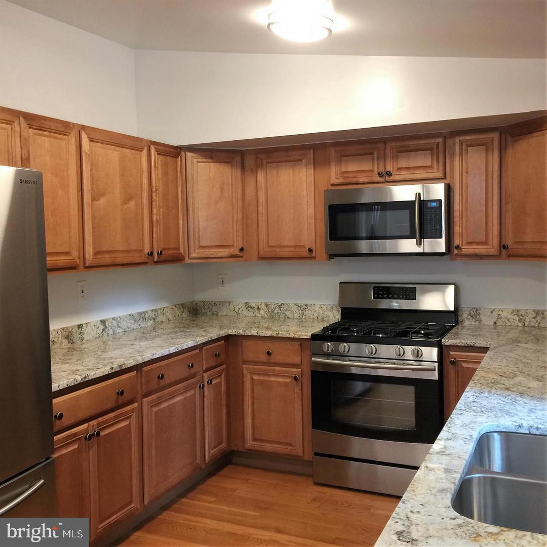 2312 Whitetail Court Reston, VA 20191 - Photo 7 of 26 a kitchen with granite countertop a stove top oven microwave and cabinets
