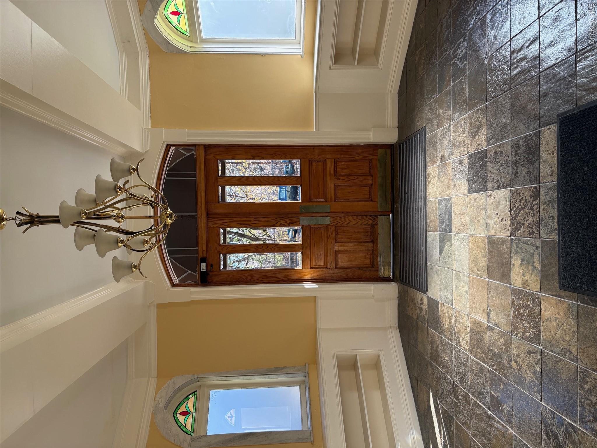 85 Bronx River Road, Unit 3S Yonkers, NY 10704 - Photo 3 of 27 Entrance foyer featuring wainscoting, a chandelier, stone tile floors, healthy amount of natural light, and a decorative wall