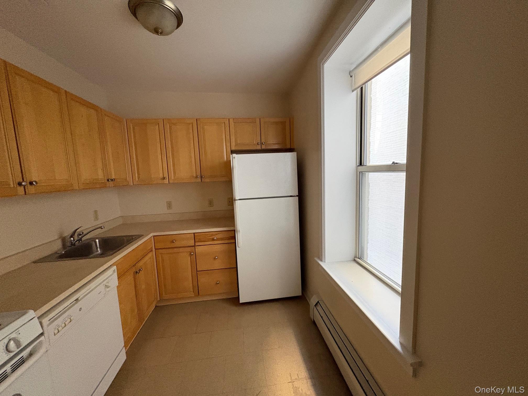 85 Bronx River Road, Unit 3S Yonkers, NY 10704 - Photo 9 of 27 Kitchen with a baseboard radiator, white appliances, light countertops, light floors, and light brown cabinetry