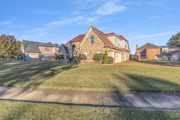 a view of a big house with a big yard and large trees