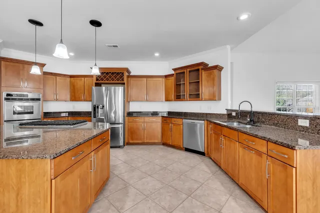 a large kitchen with stainless steel appliances a sink a counter top space cabinets and a wooden floor