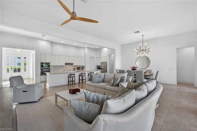 a living room with furniture kitchen view and a chandelier