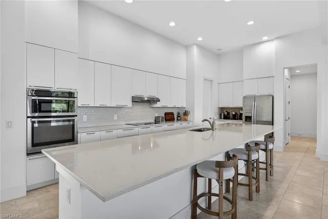 a kitchen with stainless steel appliances granite countertop a table chairs sink refrigerator and microwave