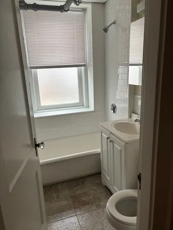 a bathroom with a tub a sink and a window