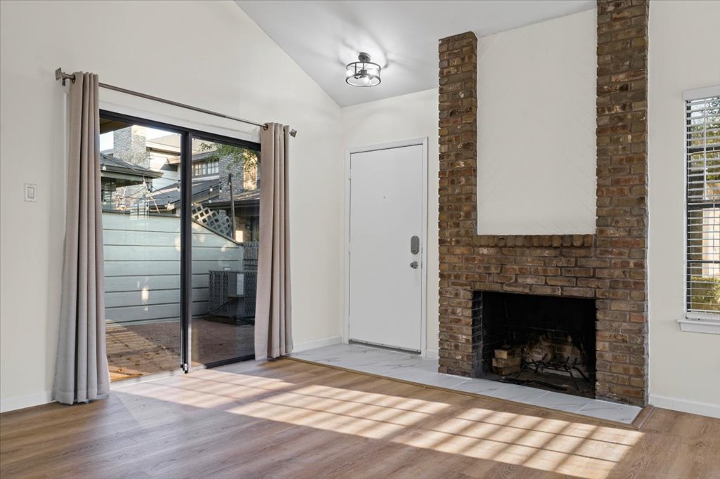 1748 Ohlen Road, Unit 75 Austin, TX 78757 - Photo 10 of 33 Unfurnished living room with light wood-style flooring, lofted ceiling, and a brick fireplace
