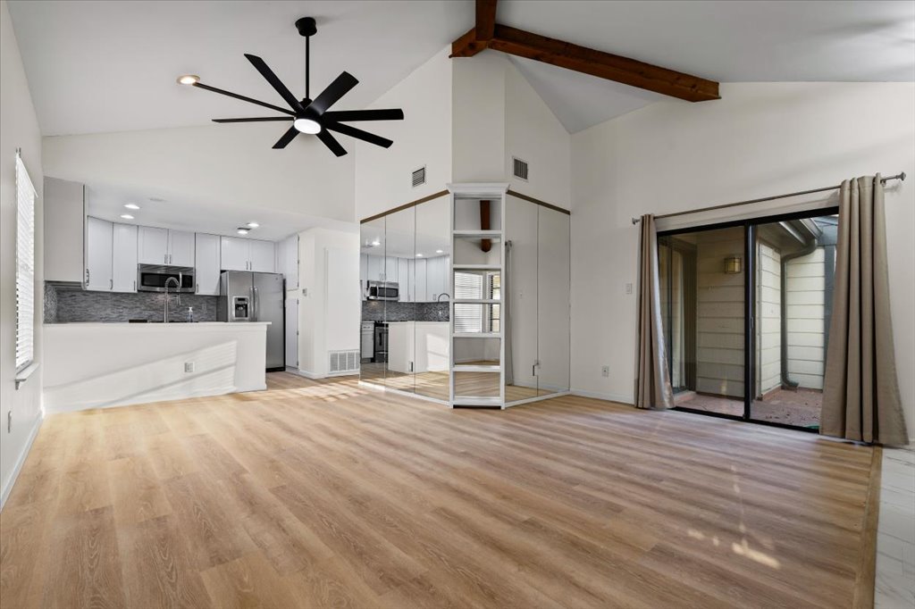 1748 Ohlen Road, Unit 75 Austin, TX 78757 - Photo 14 of 33 Unfurnished living room with high vaulted ceiling, light wood-style floors, a ceiling fan, and beamed ceiling