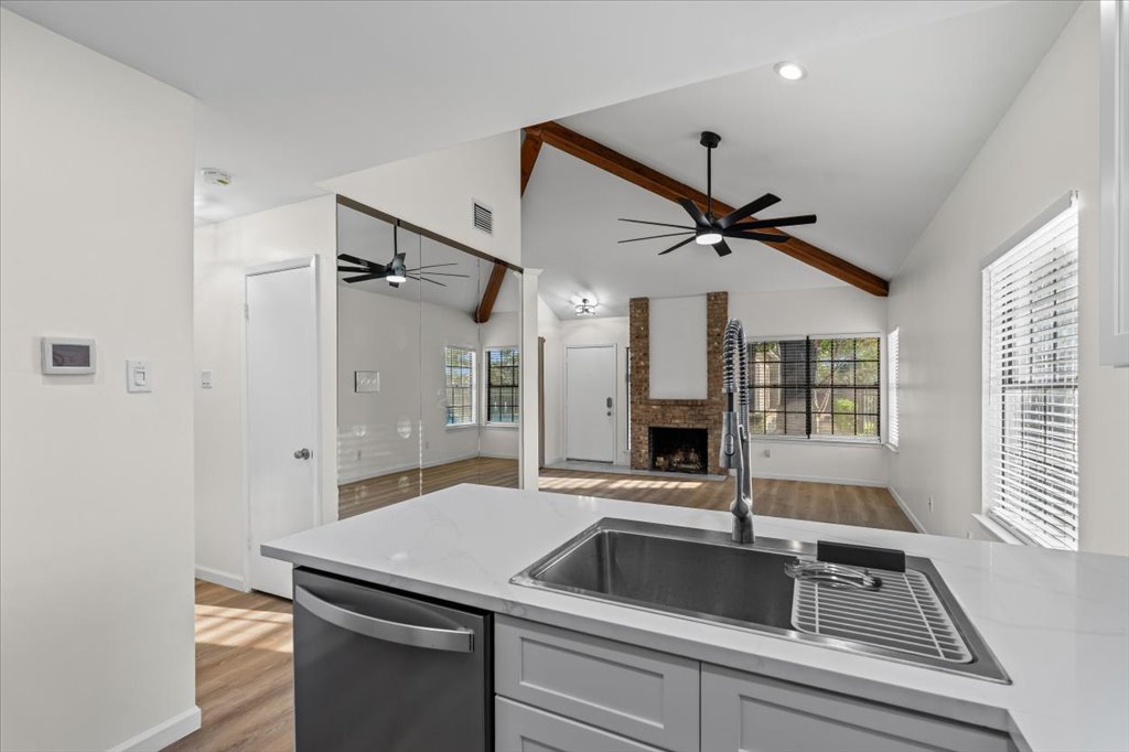 1748 Ohlen Road, Unit 75 Austin, TX 78757 - Photo 19 of 33 Kitchen with light wood-type flooring, beam ceiling, dishwasher, a brick fireplace, and ceiling fan