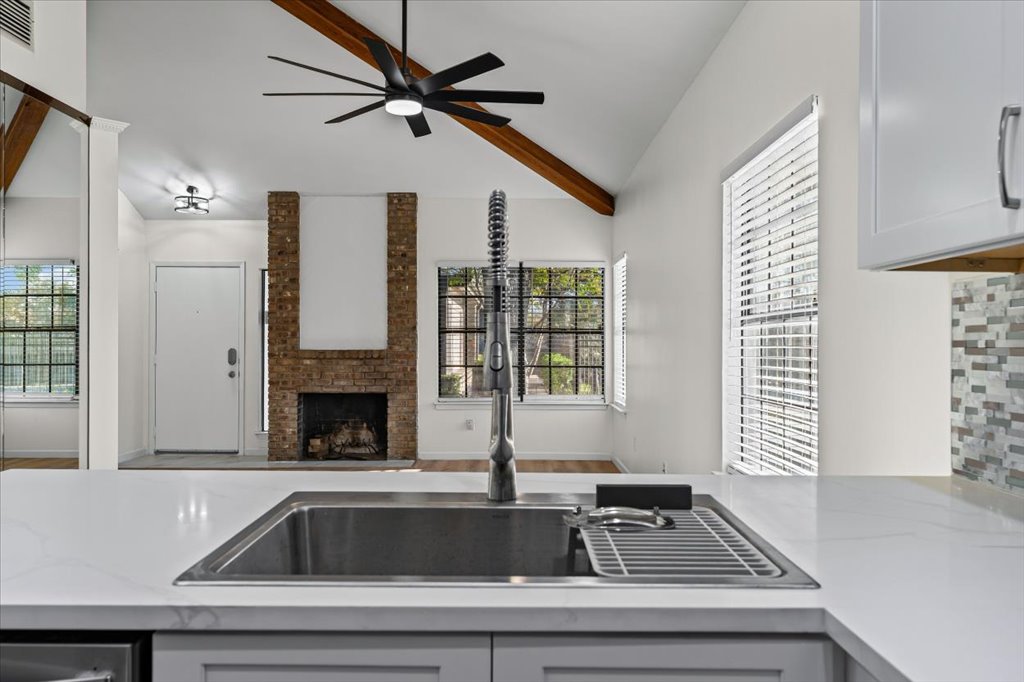 1748 Ohlen Road, Unit 75 Austin, TX 78757 - Photo 33 of 33 Kitchen featuring a fireplace, open floor plan, light stone counters, ceiling fan, and backsplash
