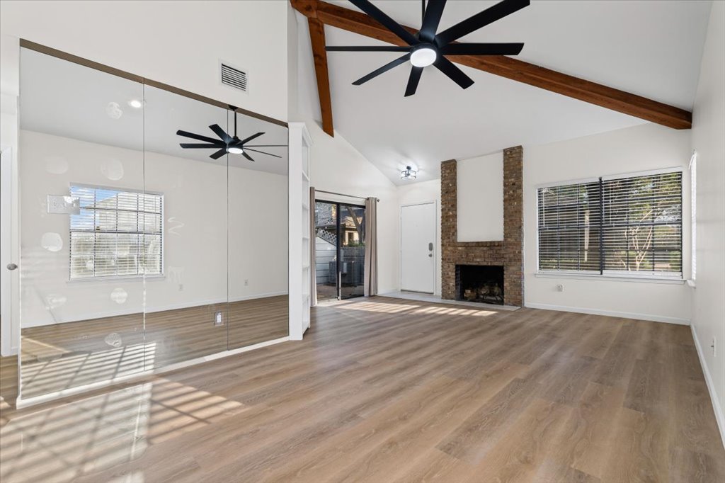 1748 Ohlen Road, Unit 75 Austin, TX 78757 - Photo 9 of 33 Unfurnished living room featuring high vaulted ceiling, a fireplace, light wood finished floors, ceiling fan, and beamed ceiling