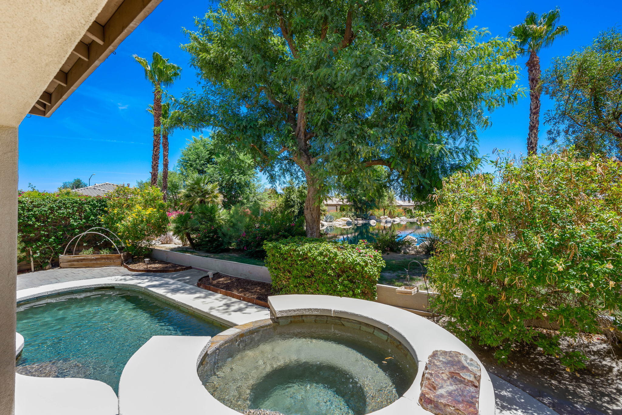 49728 Pacino Street Indio, CA 92201 - Photo 50 of 54 a swimming pool with outdoor seating and green bushes