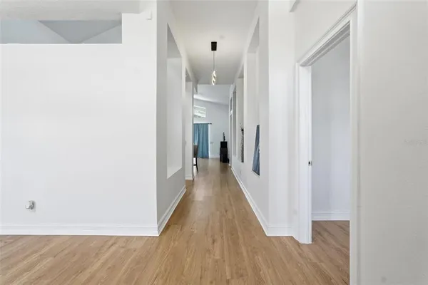 a view of a hallway with wooden floor and a bathroom