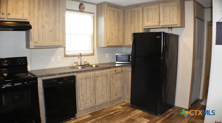 12240 Fm 1383 Schulenburg, TX 78956 - Photo 18 of 24 a kitchen with granite countertop white cabinets and refrigerator