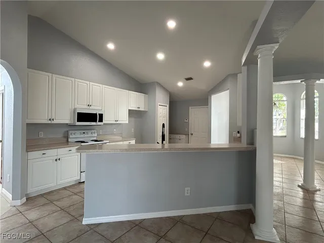 a large kitchen with kitchen island a sink a stove a refrigerator and white cabinets