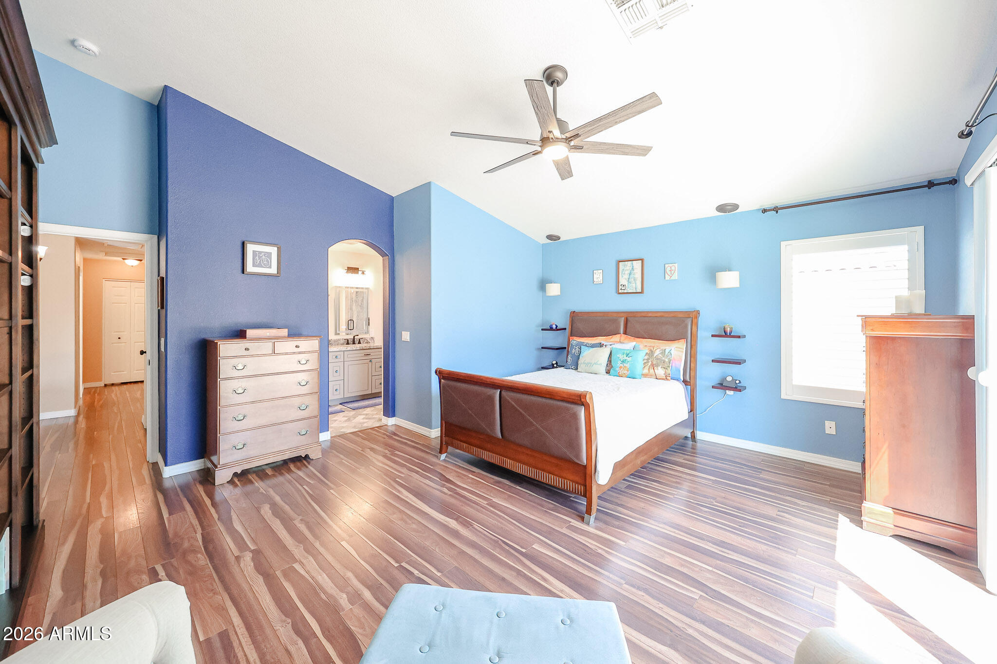 6939 West Phelps Road Peoria, AZ 85382 - Photo 14 of 29 a spacious bedroom with a bed a dresser and wooden floor