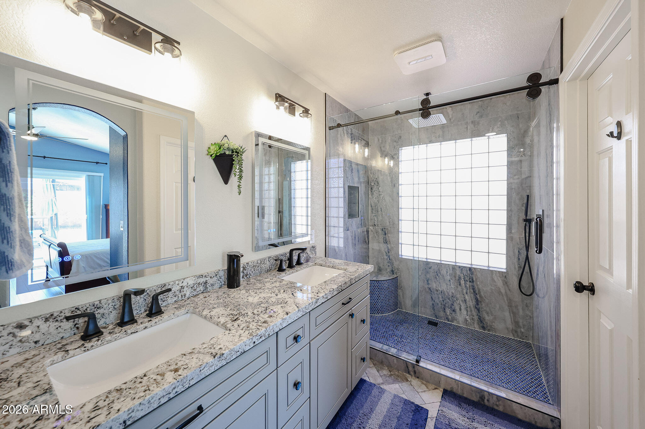6939 West Phelps Road Peoria, AZ 85382 - Photo 15 of 29 a bathroom with a granite countertop sink mirror and a shower