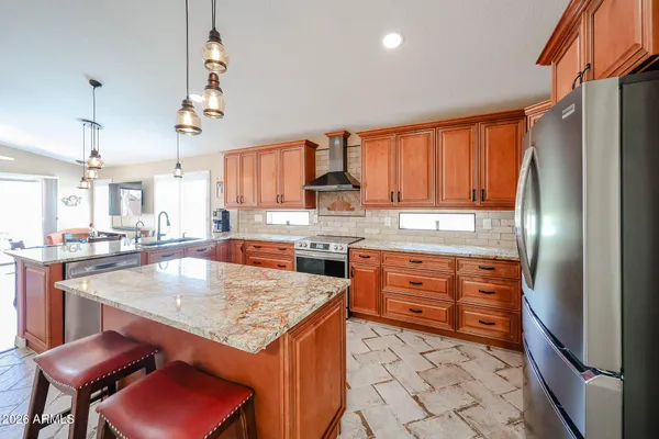 a kitchen with stainless steel appliances granite countertop a refrigerator a sink dishwasher a stove and white countertops with cabinets